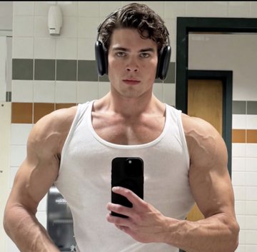 The image features a muscular man wearing headphones, holding up his phone with a selfie of himself taking the picture. The caption reads "BITCOIN 80K MAY vs bitcoin 60k june", which suggests that the photo might be related to Bitcoin or cryptocurrency news and events.