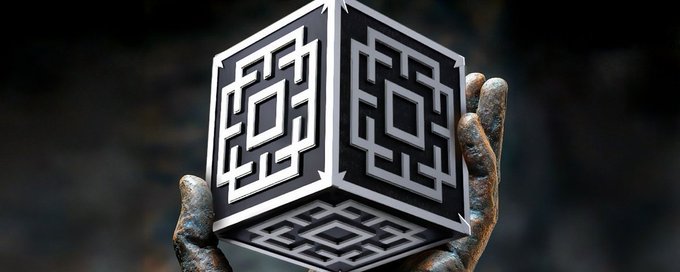 A weathered, statue-like hand holds a metallic cube adorned with intricate geometric maze patterns, symbolizing complexity and hidden pathways. The imagery visually echoes the post's description of Emblem as a multifaceted platform where launching a token is intricately connected to broader tools like AI app development and cross-ecosystem deployment, representing the interconnected "maze" of features users can navigate.
