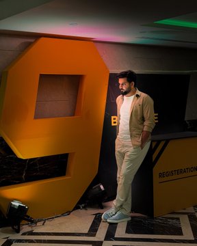A man poses beside a large illuminated orange "9" sculpture at a Binance 9th Anniversary event, with a "REGISTRATION" desk visible to the right, marking his attendance at the Islamabad celebration as a longtime trader since 2020.