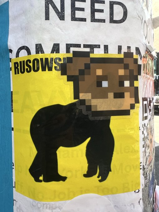 A yellow "COMPETITION" poster features a silhouette of a gorilla with the head replaced by a pixelated ape/NFT-style graphic, partially covering the word "RUSOWSKI." The image's edgy, meme-like aesthetic fits with a crypto/NFT community post from CryptoSpacesNetwork.