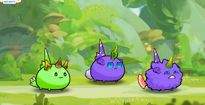Three cartoon Axie Infinity characters—a green axie, a purple axie, and a fluffy purple axie—stand in a lush green forest setting.