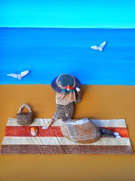 A miniature beach scene features a small figure wearing a blue sun hat seated on a striped beach towel beside a woven bag, with two white butterflies flying against a vibrant blue ocean and sky backdrop. The summery, playful setting visually echoes the post's "Born in the Heart of Summer" theme and midsummer party hashtags, suggesting a 1/1 NFT titled "Happy Saturday."