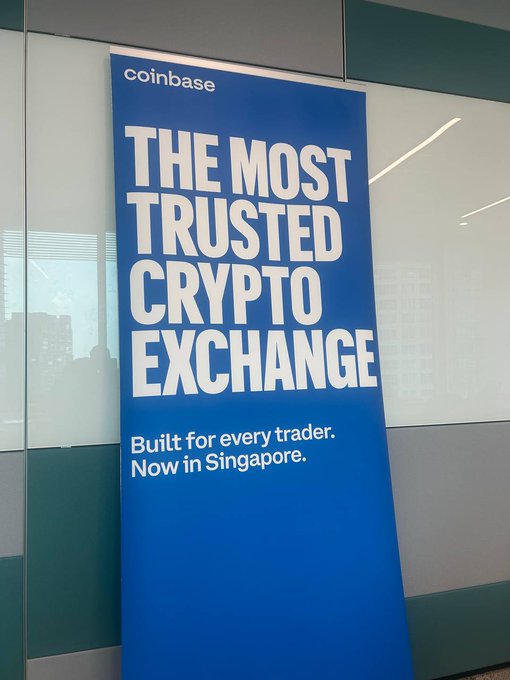 A blue Coinbase promotional banner reading 'THE MOST TRUSTED CRYPTO EXCHANGE' with the tagline 'Built for every trader. Now in Singapore.'