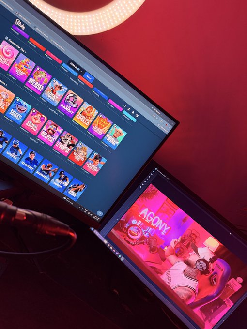A setup featuring a computer monitor displaying a Stake online casino interface alongside a laptop screen showing an 'AGONIX' slot game, suggesting online gambling.