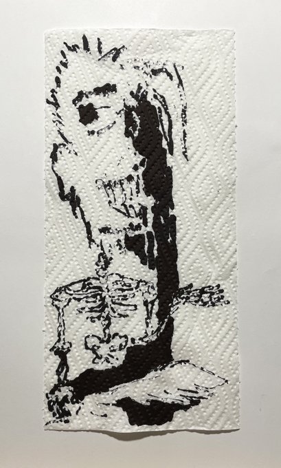 A piece of black ink art on a textured white paper towel depicting a skeletal or undead figure with a distressed face, reminiscent of horror/zombie illustration.