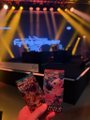 Small image of a concert stage with bright yellow spotlights illuminating performers during a live music event.