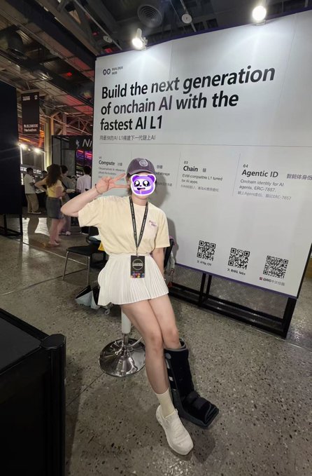 A photo of a person posing in front of an advertisement that reads 'Build the next generation of onchain AI with the fastest AI L1', pointing to text listing 'Compute', 'AI Chain', and 'Agentic ID'.