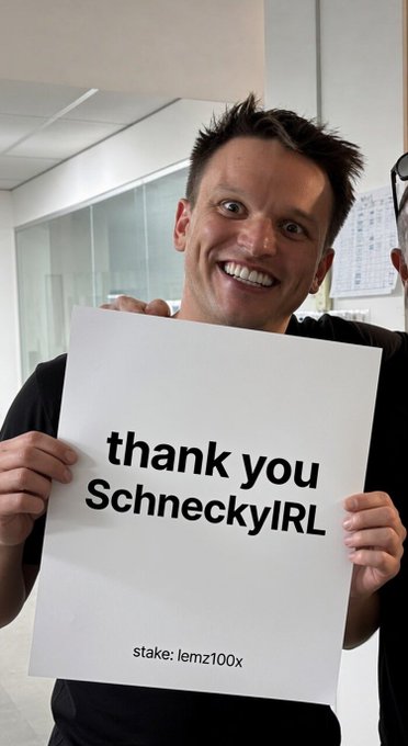 A smiling man holds a sign that reads 'thank you SchneckyIRL' with 'stake: lemz100x' written at the bottom.