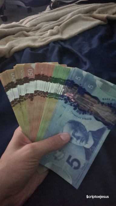 A hand holding a fan of various international banknotes, including a $5, $50, and other denominations, with the watermark '$criptojesus' in the corner.