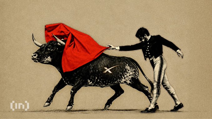 A vintage-style illustration shows a matador in a black jacket and striped pants waving a red cape at a charging bull, with a small '[in]' watermark in the bottom left corner.