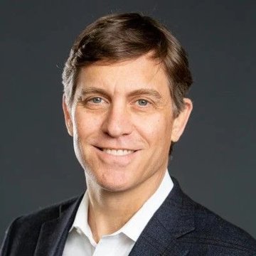 The photo shows a smiling man with short brown hair wearing a dark blazer over a white shirt, consistent with a professional headshot of Franklin Templeton's Chris Perkins referenced in the post. The image pairs with the news about Perkins expressing confidence in crypto's future regardless of the CLARITY Act's passage, citing upcoming SEC and CFTC regulatory precedent under Atkins and Selig.