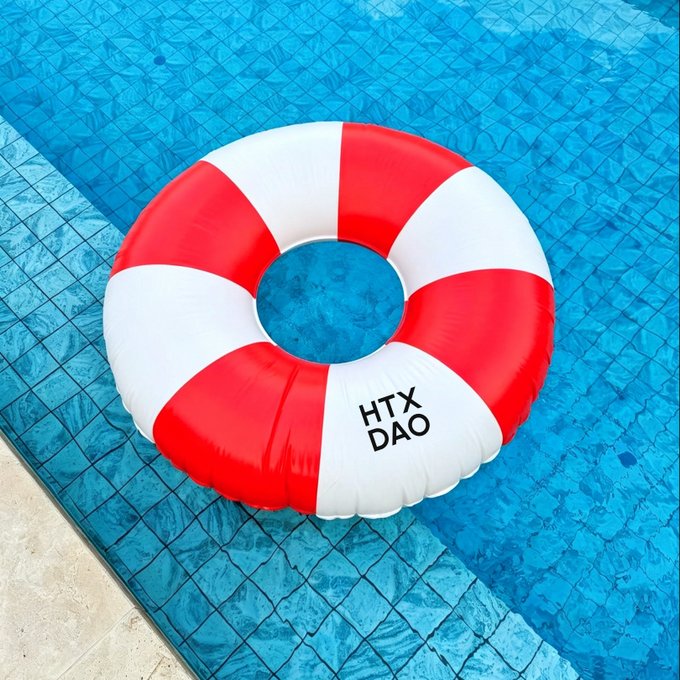 A red and white striped inflatable life ring floats in a blue tiled swimming pool, displaying the text "HTX DAO." The poolside scene evokes a summer vibe, fitting the post's playful greeting about the day's temperature.