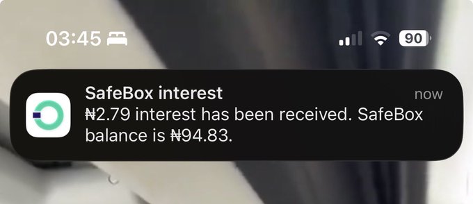 An iPhone notification at 03:45 from SafeBox states '₦2.79 interest has been received. SafeBox balance is ₦94.83.' with the battery at 90%.