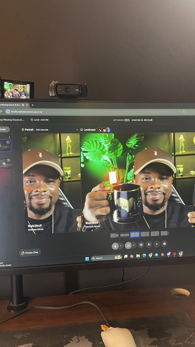 A computer monitor displays Studio Live editing software showing photos of a man holding a mug, with a webcam and another screen mounted on top.