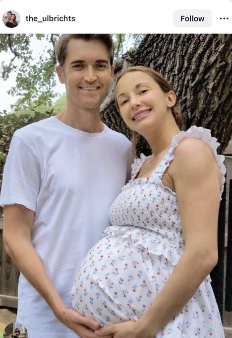 The Instagram post from @the_ulbrichts shows a smiling couple posing outdoors by a tree, with the man in a white t-shirt cradling the visibly pregnant woman's belly as she wears a floral sundress, accompanying an announcement that Silk Road founder Ross Ulbricht is expecting his first child two years after being freed from prison, crediting Bitcoin for his newfound freedom.