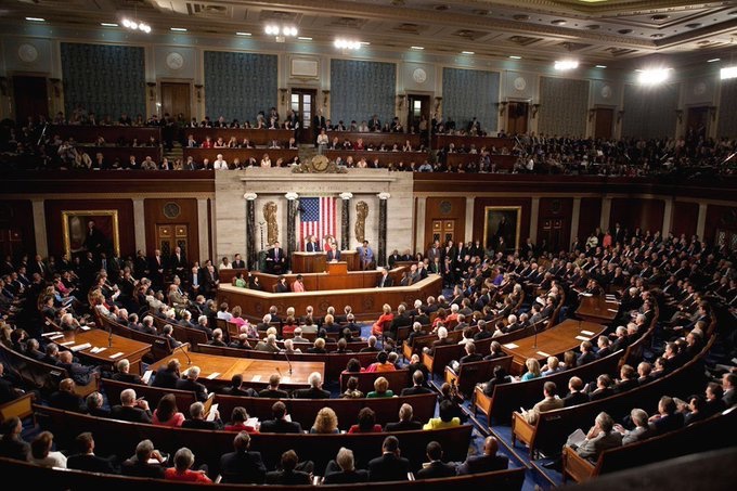 A wide-angle view of the U.S. House of Representatives chamber during a joint session, with members of Congress seated in the audience and officials at the Speaker's rostrum in front of an American flag.