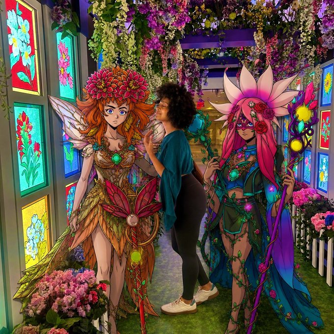 A woman stands admiring two elaborate, fairy-like digital art murals in a vibrant floral garden display, symbolizing the opportunity to discover and collect artistic NFTs early before their value surges in the market.