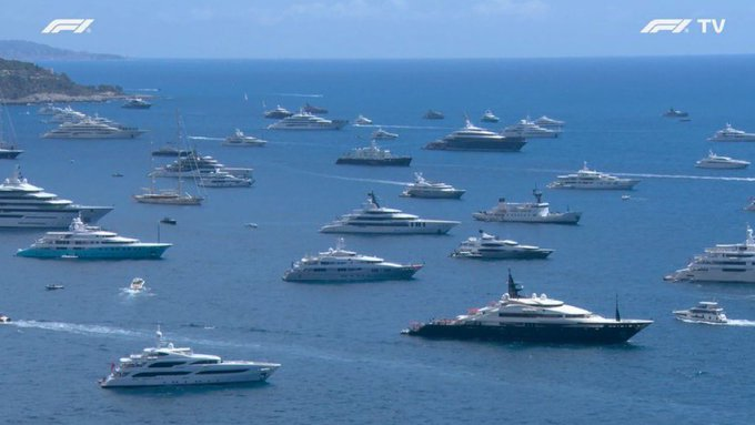 Aerial view of numerous luxury yachts gathered on bright blue water, with F1 and F1 TV logos in the top corners.