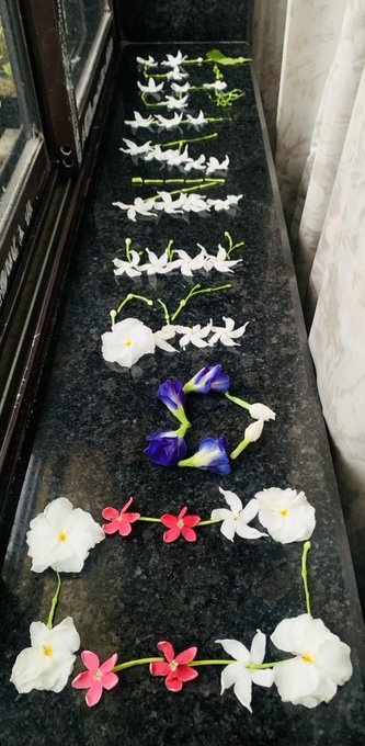 A collection of small, colorful artificial flowers (white, pink, and blue) arranged neatly on a dark granite windowsill.