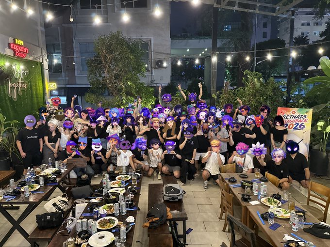 A group photo from what appears to be a Vietnam Crypto community meetup, with attendees posing with purple and black character masks, including a 'VIETNAM BLOCKBACK 2026' banner in the background.