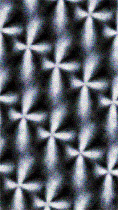 A monochrome abstract pattern of repeating three-dimensional star or diamond shapes with grainy texture.