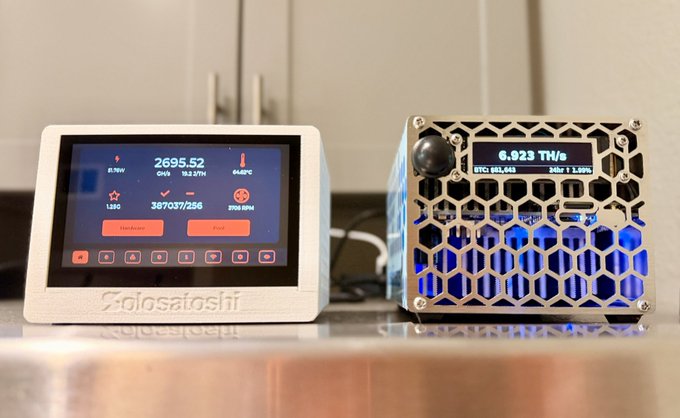 Two cryptocurrency mining devices, including a 'Golosatoshi' display and a unit showing 0.923 TH/s, sitting on a table.