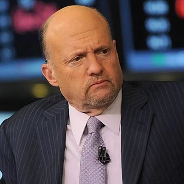 Jim Cramer is pictured in a studio setting wearing a dark pinstripe suit and patterned tie, his face showing a serious, slightly grim expression that suggests regret or concern. The image relates to the post by highlighting Cramer's past dismissive remarks about cryptocurrency, as Bitcoin has since tripled in value.