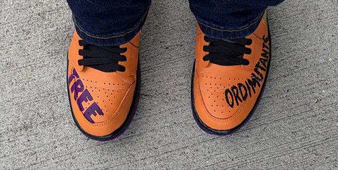 A pair of orange sneakers with black laces and purple soles, featuring the words "FREE" on one toe and "ORDINUTANTS" on the other.