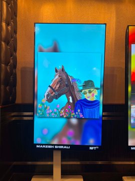 A vibrant digital artwork displayed on a screen at an NFT NYC event features a stylized cowboy figure alongside a horse and cactus, with the text "MANDEEH DHOBALI" and "NFT" visible at the bottom. The piece exemplifies the colorful, generative style being showcased in the Edison's gallery during the conference.