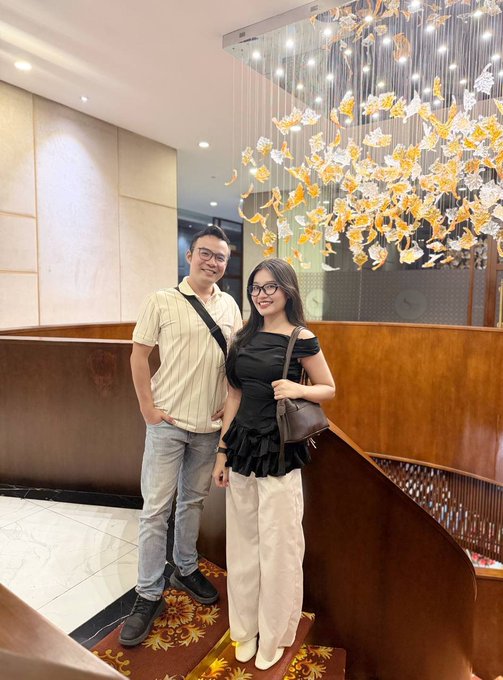 Two smiling friends pose together beneath an elegant golden chandelier in what appears to be a hotel lobby, capturing a memorable reunion moment at the Conviction event after knowing each other since the Ritual project.