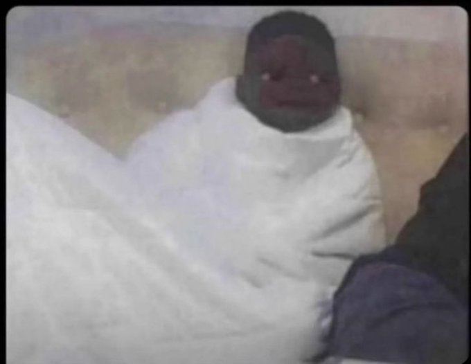 A person bundled tightly in a white blanket with only their face visible, shivering in cold weather, visually illustrating the post's complaint about the harsh weather affecting them.