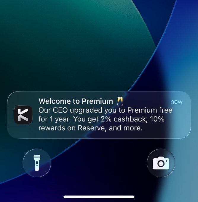 A phone notification from an app reads 'Welcome to Premium 🥂 Our CEO upgraded you to Premium free for 1 year. You get 2% cashback, 10% rewards on Reserve, and more.'