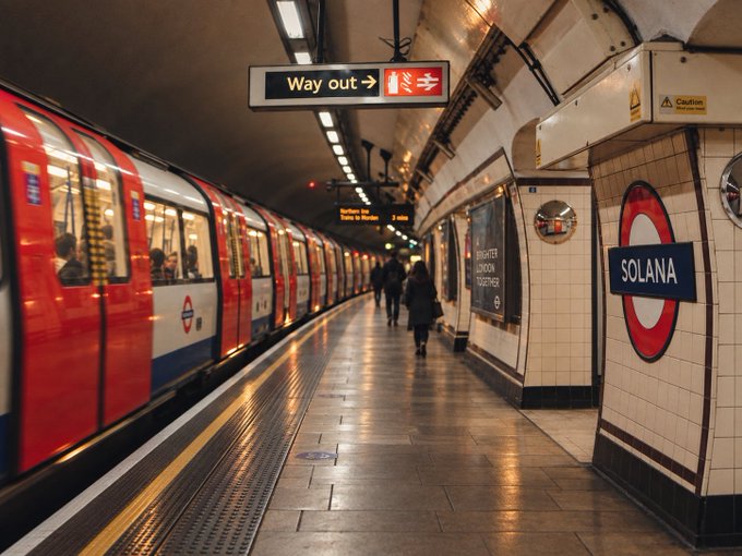 A view down a subway platform with a red train on the left and a station sign reading 'SOLANA' on the right wall.