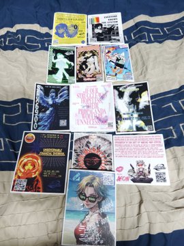 A collection of SPX6900 (#SPX6900) themed stickers spread out on a bedspread, featuring designs including "1000X OR NOTHING," "INVEST IN PEACE," "$SPX," and character art including what appears to be a sunglasses-wearing mascot. The stickers showcase various crypto-meme artwork being received and laid out for application, matching the excitement of the post about new SPX6900 merchandise arriving.
