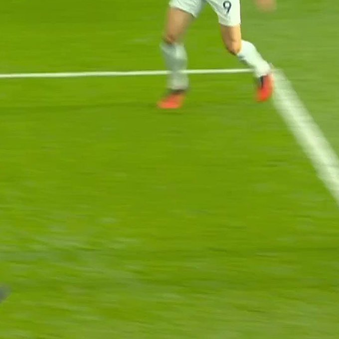 A blurry action shot of a soccer player wearing white shorts with the number 9 and red cleats running across a green field.