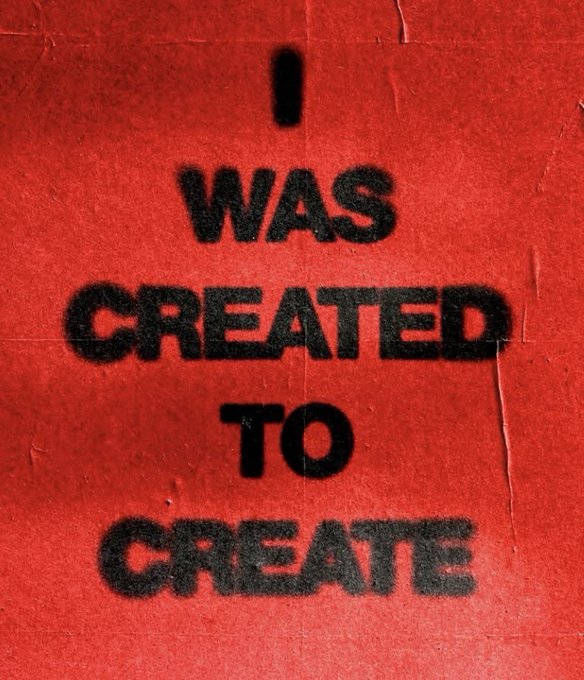 A red poster with stenciled black text reading 'I WAS CREATED TO CREATE'.