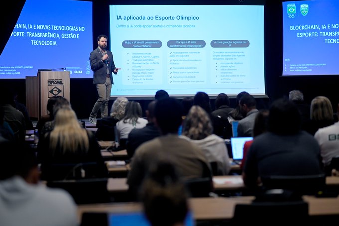 A presenter delivers a workshop on AI applied to Olympic sport at an event in Brazil, with slides displaying topics like transparency, management, and technology in sports. The presentation appears to be part of the partnership between the Brazilian Olympic Committee and a technology provider, aimed at training over 160 participants from COB and 26 National Sports Confederations on blockchain and AI fundamentals.