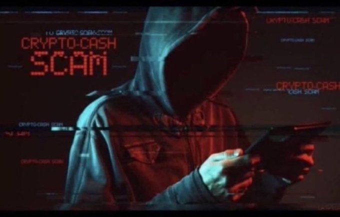 A dark, glitch-effect image of a hooded figure using a smartphone with glowing red digital text overlay reading 'CRYPTO-CASH SCAM.'