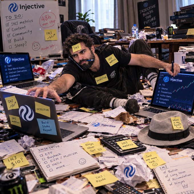 A visibly overwhelmed man is sprawled across a chaotic desk covered in Injective-branded sticky notes (listing items like "48h non stop," "INJ metrics," "Build Stake Repeat," and "Ninja Meter Golf" on May 4th) while surrounded by laptops displaying Injective (INJ) charts and trading data. The cluttered scene perfectly captures the "POV" of the frantic, over-caffeinated crypto creator struggling to craft content about the Injective blockchain token.