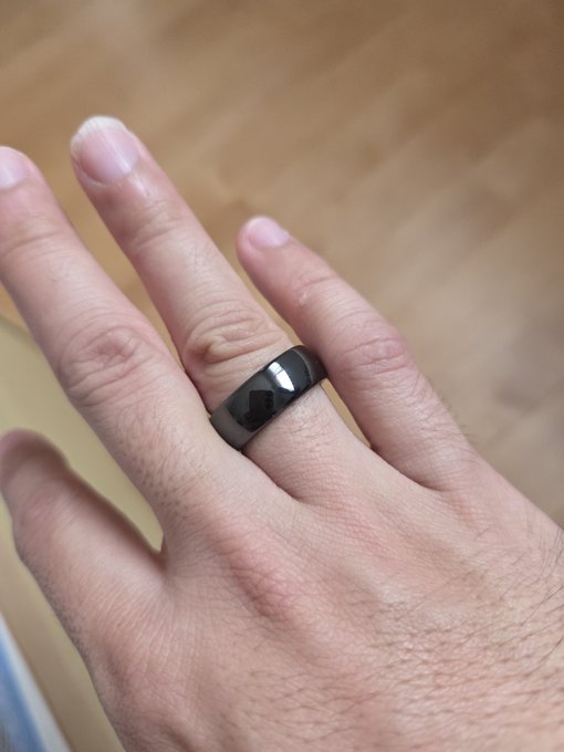 A close-up photo of a person's hand wearing a black smart ring on the ring finger.