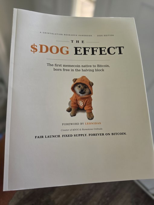 A document titled '$DOG EFFECT' described as 'A CRYPTOLUTION RESEARCH HANDBOOK 2026 EDITION,' subtitled 'The first memecoin native to Bitcoin, born free in the halving block,' featuring a Shiba Inu dog in an orange Bitcoin hoodie, with a foreword by Leonidas (creator of $DOG & Runestone Ordinals) and the tagline 'FAIR LAUNCH. FIXED SUPPLY. FOREVER ON BITCOIN.'