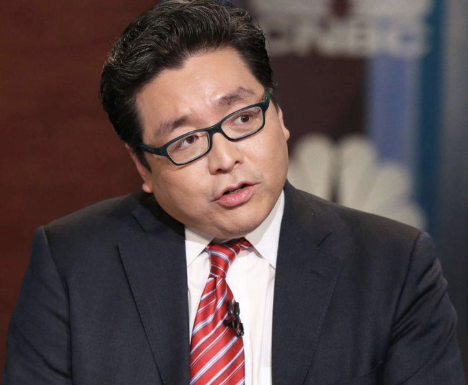 The image features a man dressed in a suit, glasses, and a red tie, sitting down with his head tilted slightly to one side as he looks at something. The background of the image has text that appears to be related to cryptocurrency and news. One description refers to "bitmine Doubles Down on $ETH Tom Lee-backed Bitmine", while another says it adds another $52M worth of Ethereum over the past week. This could possibly indicate some sort of news or event involving the crypto market, or simply a comparison between Bitmine and other cryptocurrency names.