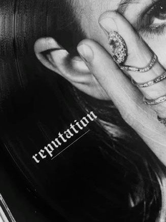 A black-and-white close-up photograph of a woman covering her face with her ring-adorned hand, with the word 'reputation' overlaid in gothic script.