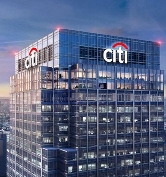 An exterior nighttime view of a modern glass skyscraper with the illuminated 'citi' logo on its facade.