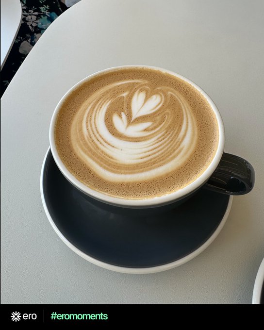 A cup of latte art coffee with a leaf design sits on a black saucer atop a white table, aligning with the post's invitation to share everyday "ero" reward moments—showing how rewards can turn into a simple coffee break. The image includes the "ero | #eromoments" branding in the bottom-left corner.