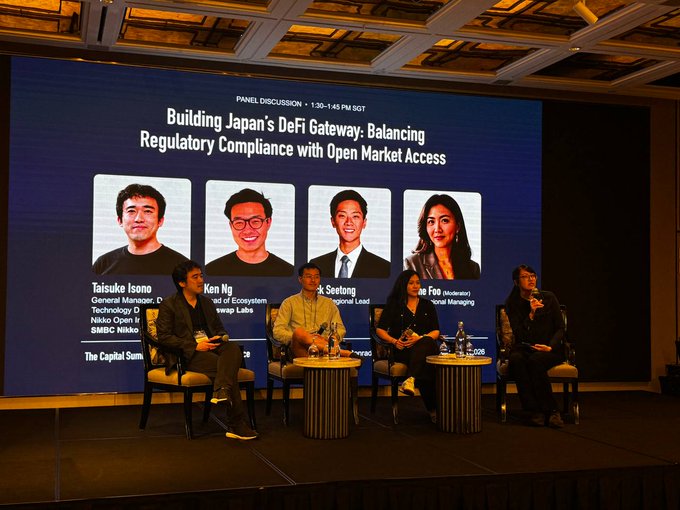 A panel discussion at 'The Capital Summit' titled 'Building Japan's DeFi Gateway: Balancing Regulatory Compliance with Open Market Access,' featuring four speakers seated on stage, with their headshots and names displayed on the large screen behind them, including Taisuke Isone, Ken Ng, and Seotong.