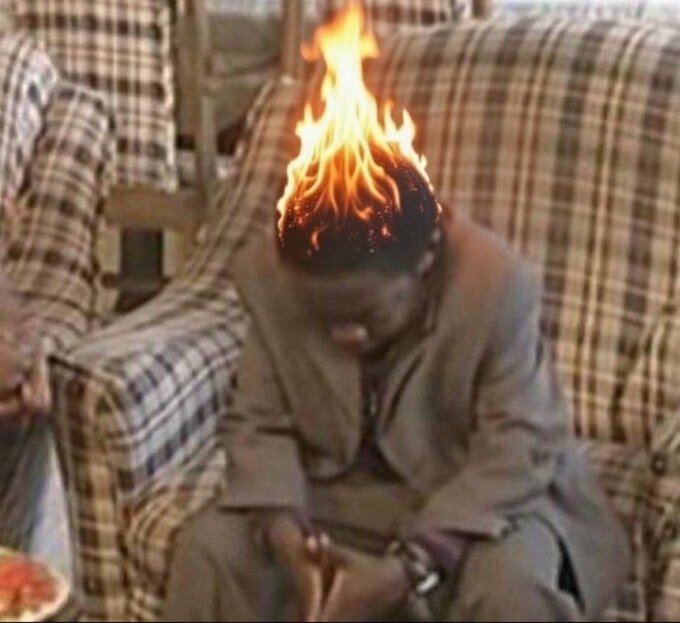 A young boy in casual clothing sits on a plaid couch with a dramatic photoshopped flame effect appearing on top of his head.