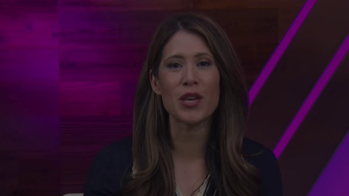 The image features a woman wearing a black top sitting at a desk or table. She appears to be talking into a microphone, possibly being interviewed for a news segment or live broadcast. The background of the image has purple and pink colors, which could indicate that she is in an office setting with a creative or artistic theme. The post also mentions that it is about space exploration and the biggest IPO in history, which might suggest that this woman is discussing the topic related to the recent SpaceX launch or other space-related events.