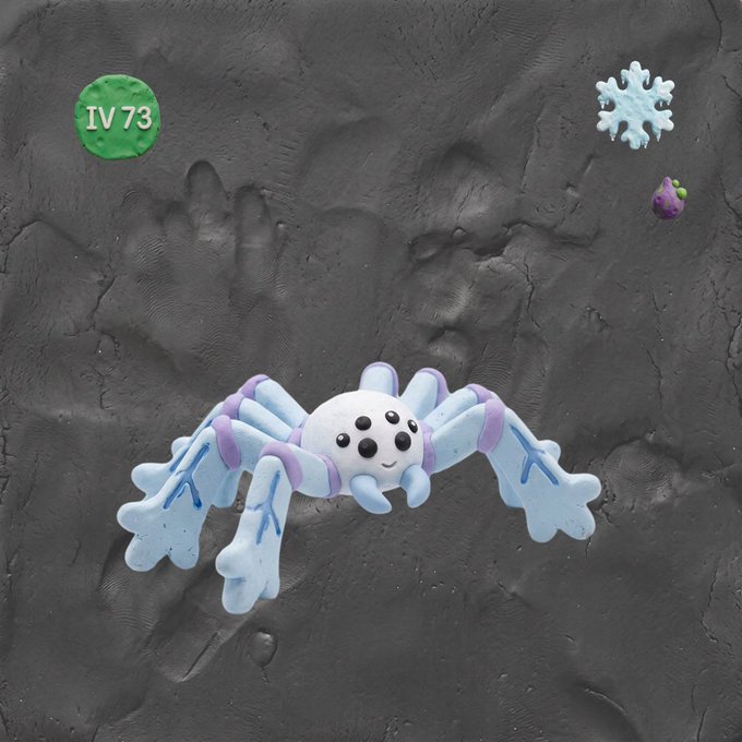 A small white and purple clay spider with multiple eyes sits on gray clay, with a green disc labeled 'IV 73' in the corner.