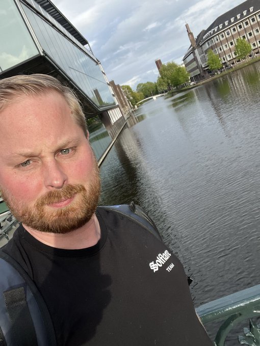 A man with a reddish beard takes a selfie while kayaking on a canal, with a wetsuit and waterfront buildings visible in the background. His black shirt displays the "Solflare Team" logo, connecting the image to the post's mention of the Solflare platform.